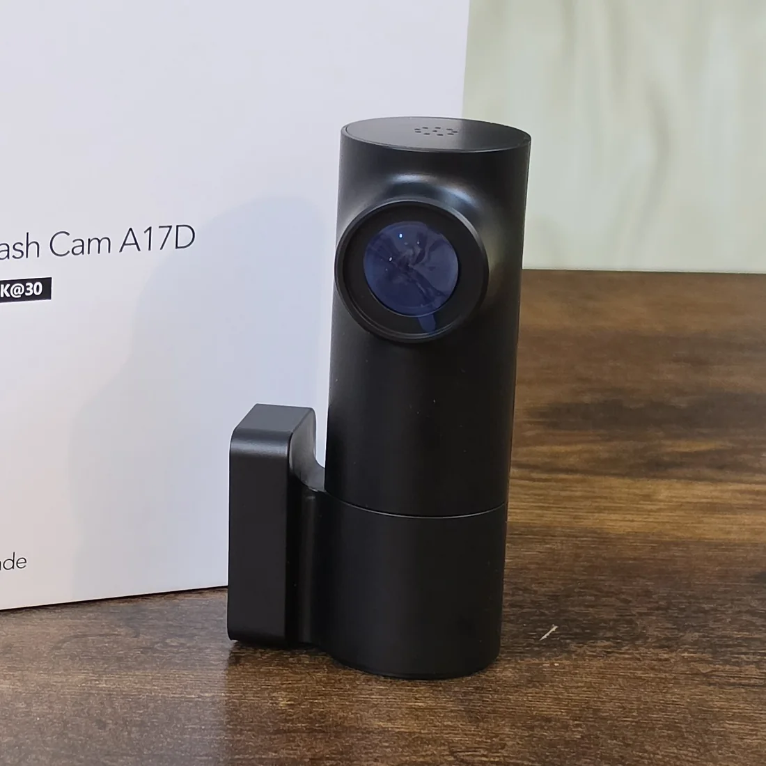 The COXPAL A17D barrel dash cam with its mount clip attached, standing on a table beside its retail box