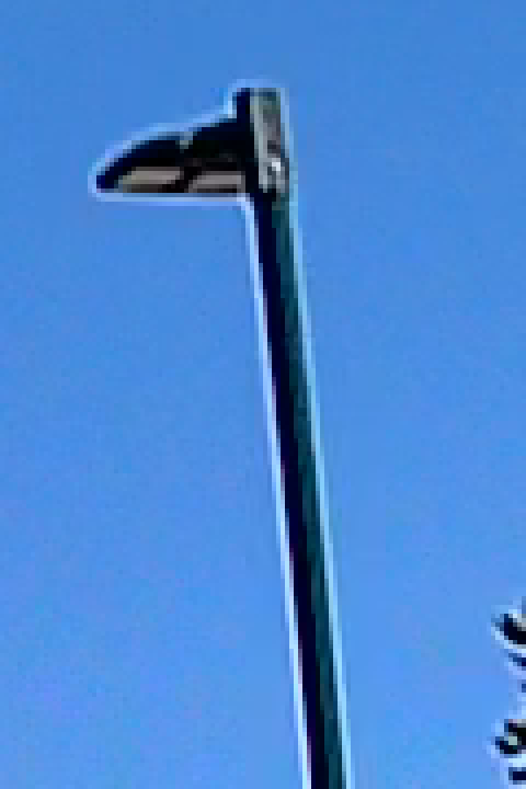 The same light pole against blue sky at four times enlargement with HDR on, the bright outline along both edges slightly fainter